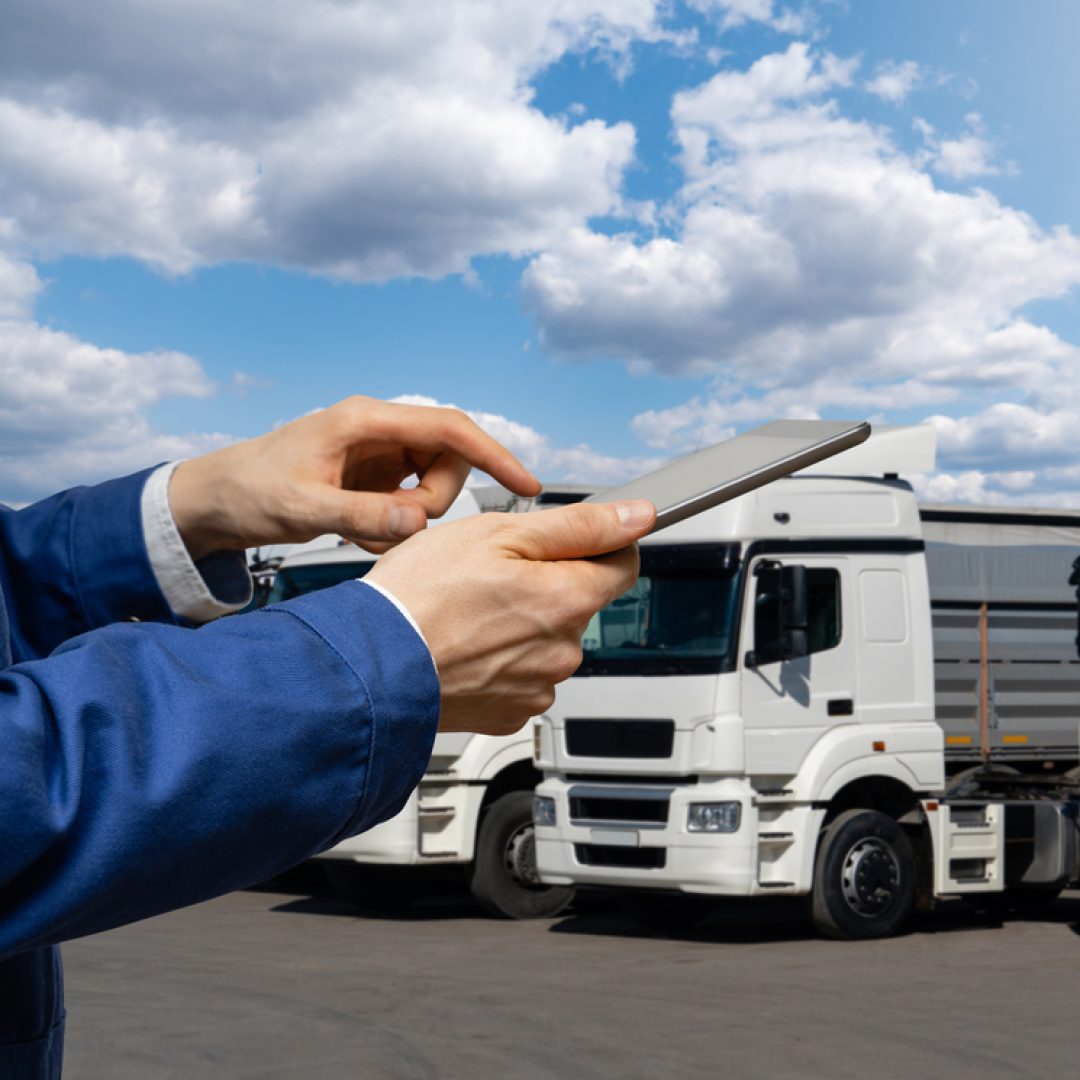 Manager with a digital tablet on the background of trucks. Fleet management